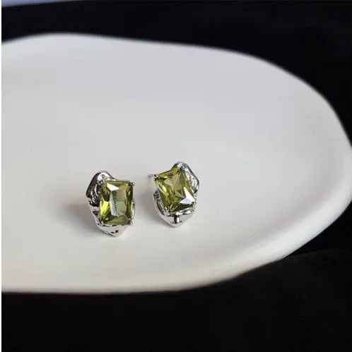 Pair of liquid olive green electroplated alloy stud earrings for women on a neutral background