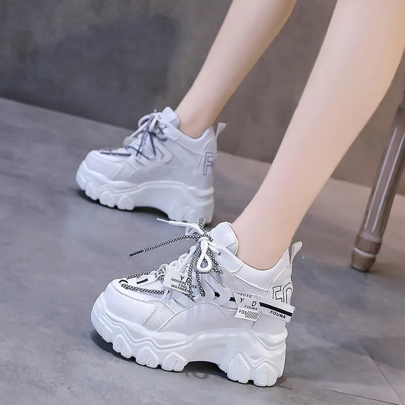 White women's low-top platform sports shoes with a cross-strap over a shallow-cut collar and a thick rubber sole.