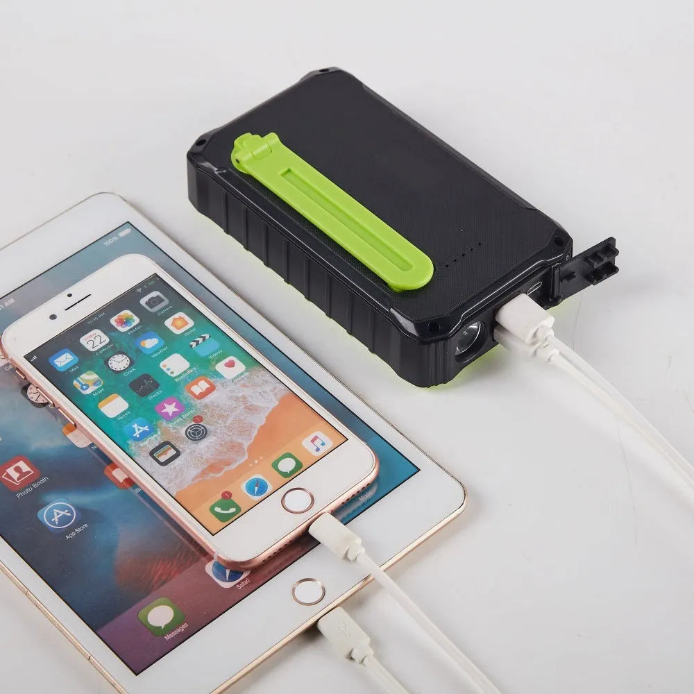 Green and orange hand solar power bank with solar panel, hand crank, and dual USB ports.