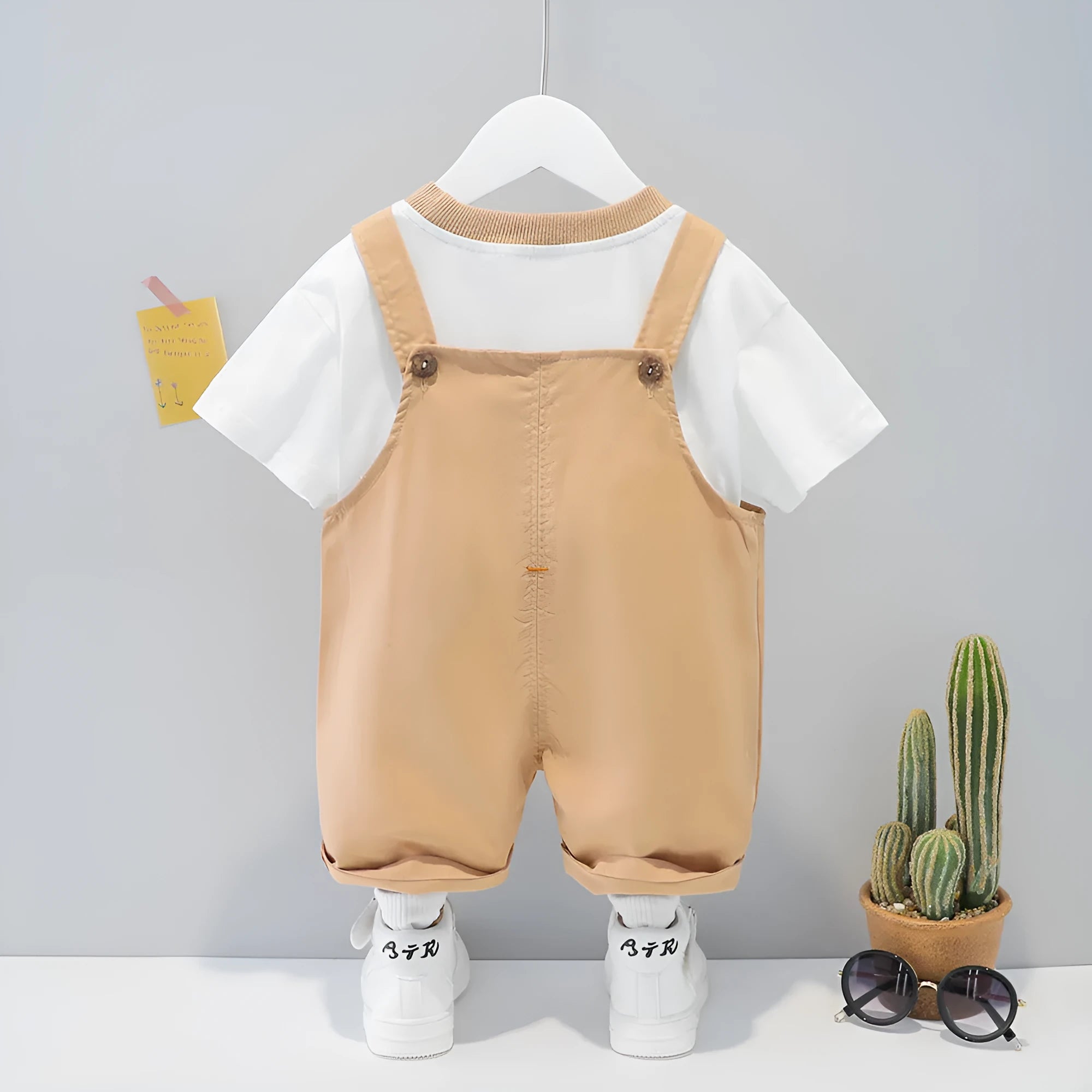 Yellow children's cotton short-sleeved romper with cartoon print and adjustable straps.