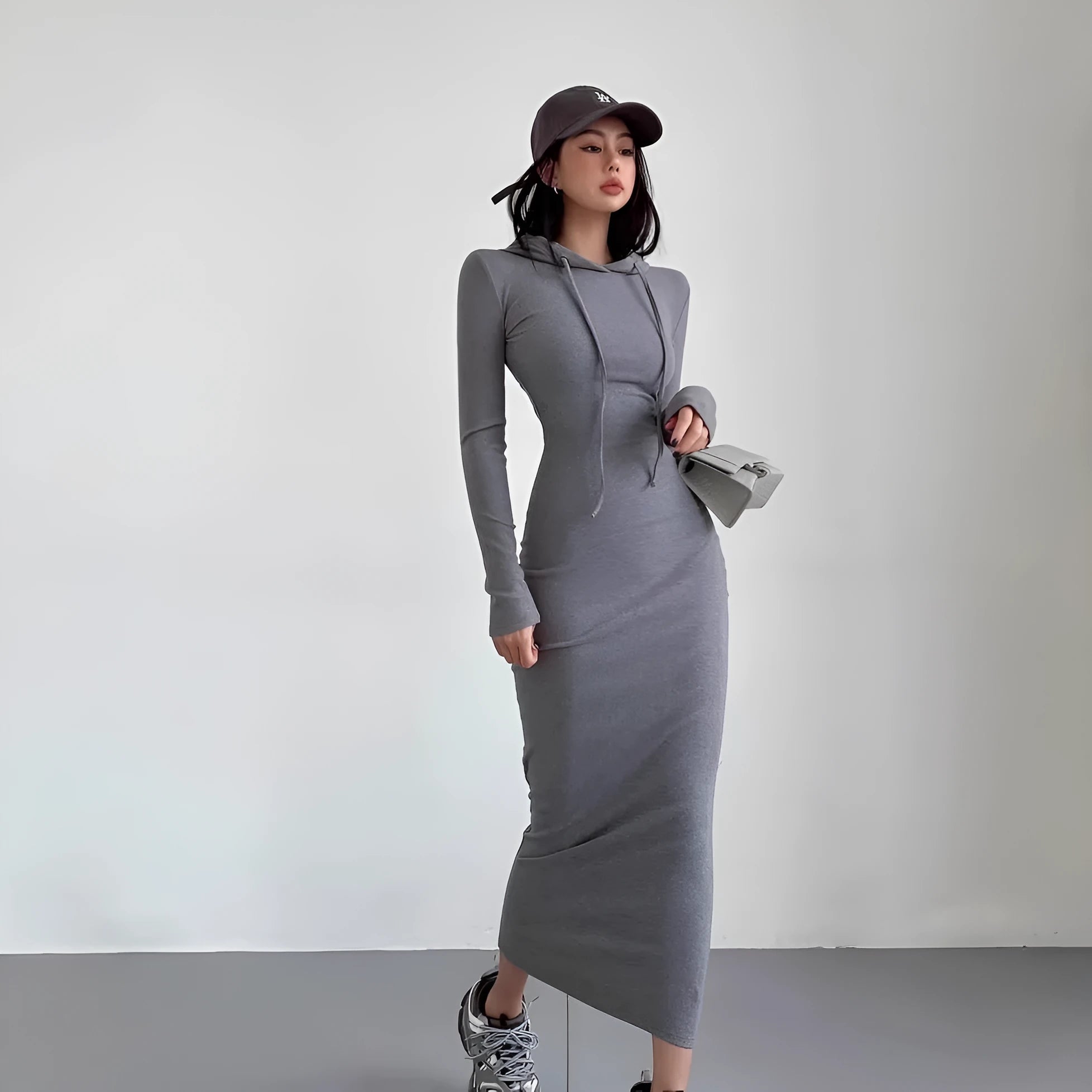 A woman modelling a grey hooded long-sleeve sheath dress with a high waist.