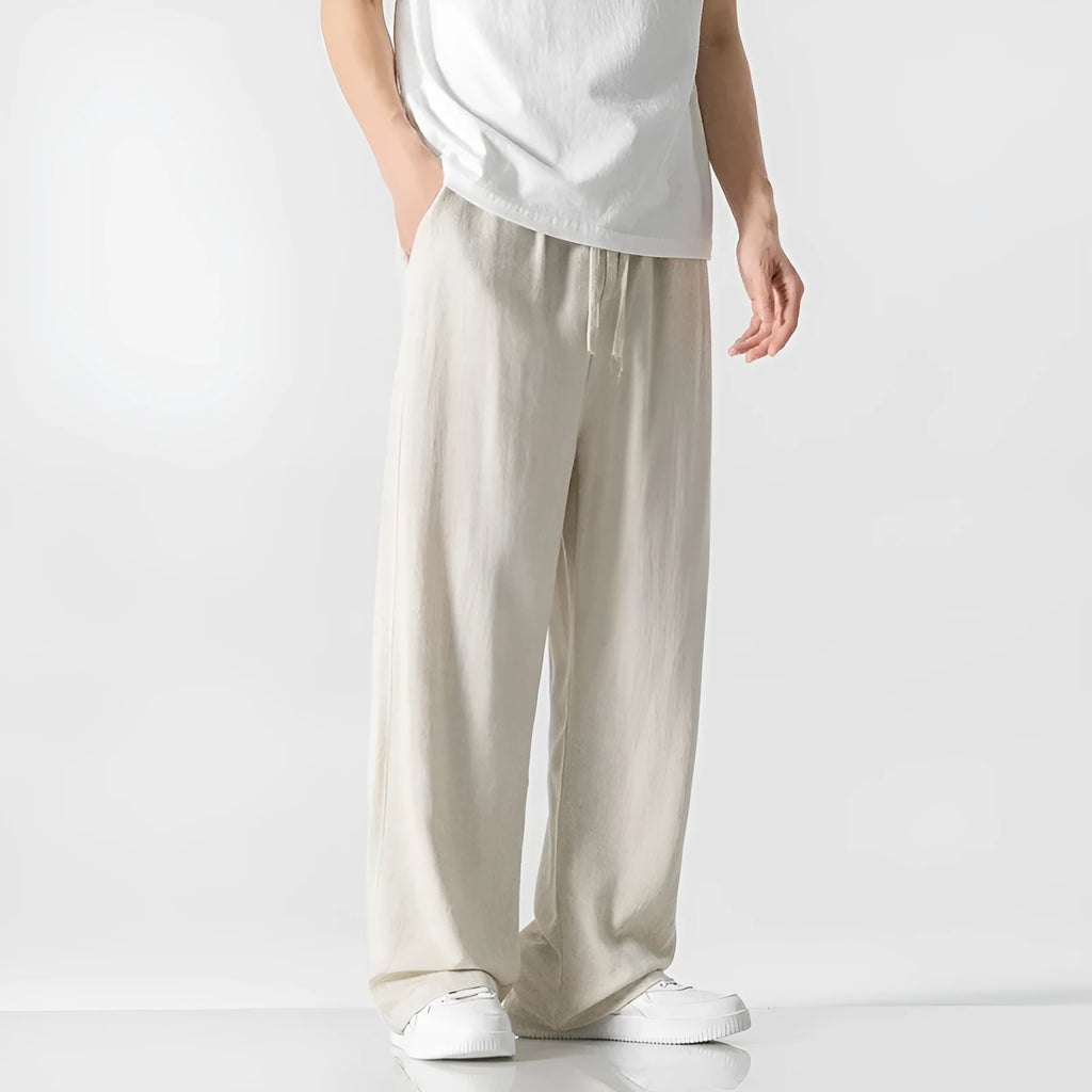 Man wearing beige bamboo fibre cropped trousers with a drawstring waist and straight legs.