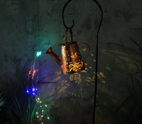 Solar-powered iron garden lamp with a tapered butterfly pattern emitting warm white light.