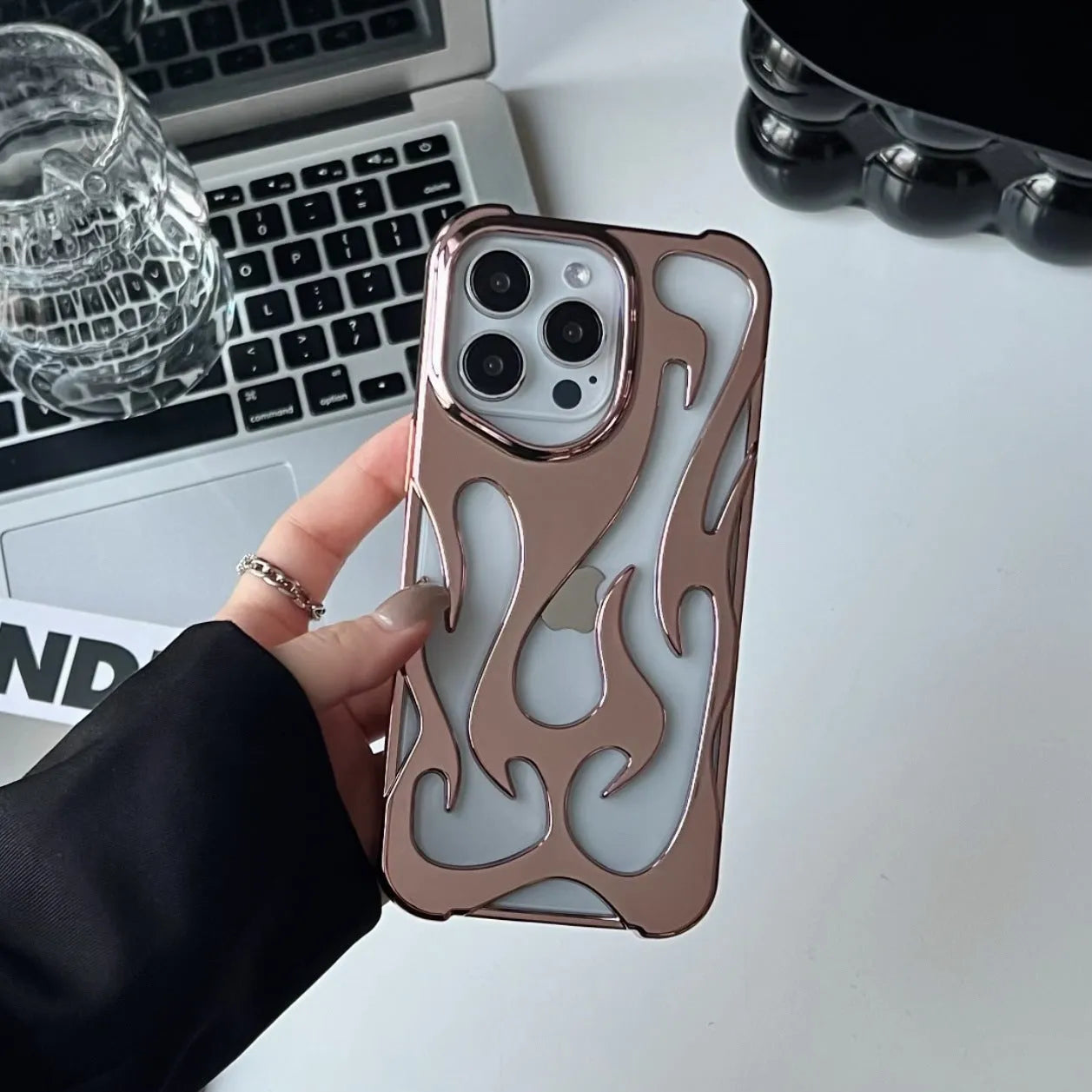 Electroplated hollow flame pattern phone case for iPhone on a table, showing silver metallic finish and cut-out design.