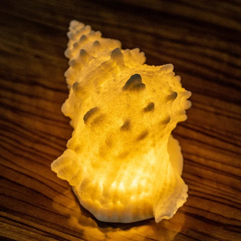 Small geometric night lamp with built-in battery in conch colour, dimensions 13 by 19 by 11 cm, on a bedside table
