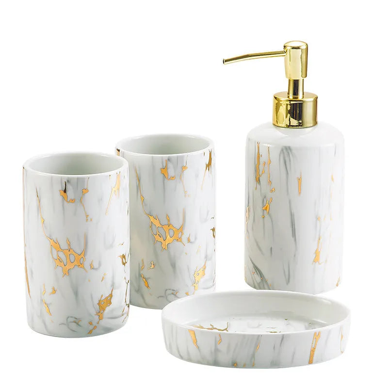 White ceramic bathroom wash kit set with two cups, a soap dish, and a bottle on a marble background.