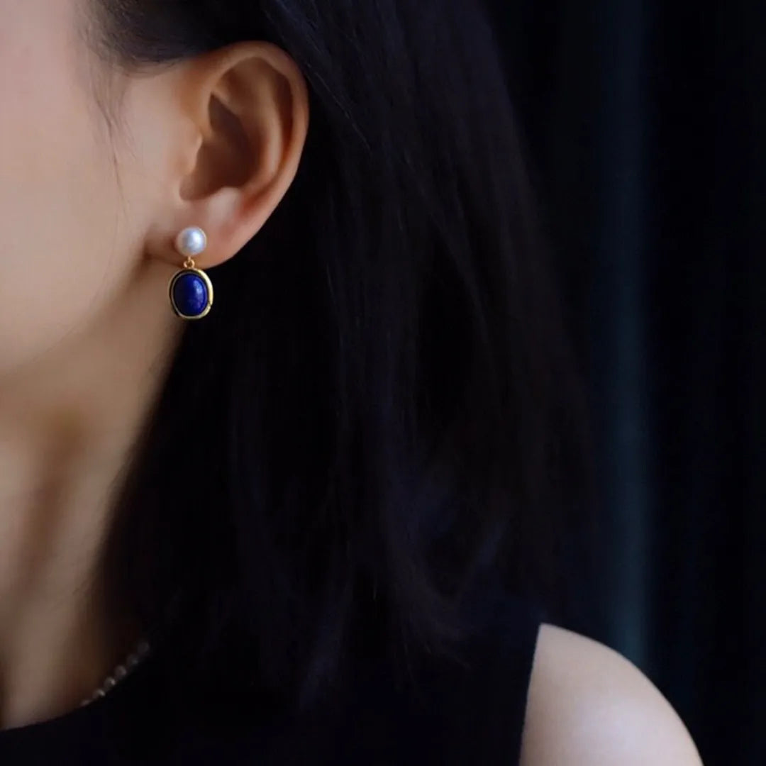 A pair of silver earrings with blue lapis lazuli pearls and auspicious patterns.