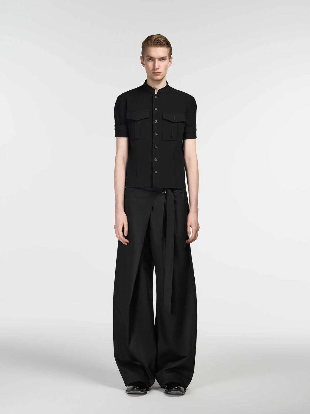 Black straight-leg trousers with adjustable waist and single pleat detail on a hanger.