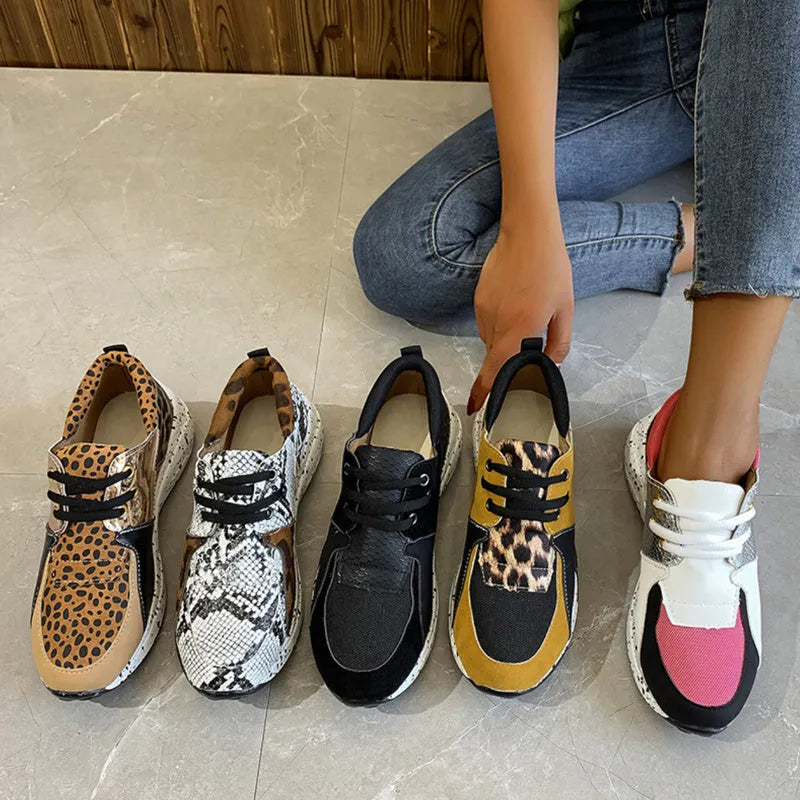 Women's black suede wedge sneakers with a low-cut ankle and round toe on a wooden floor.