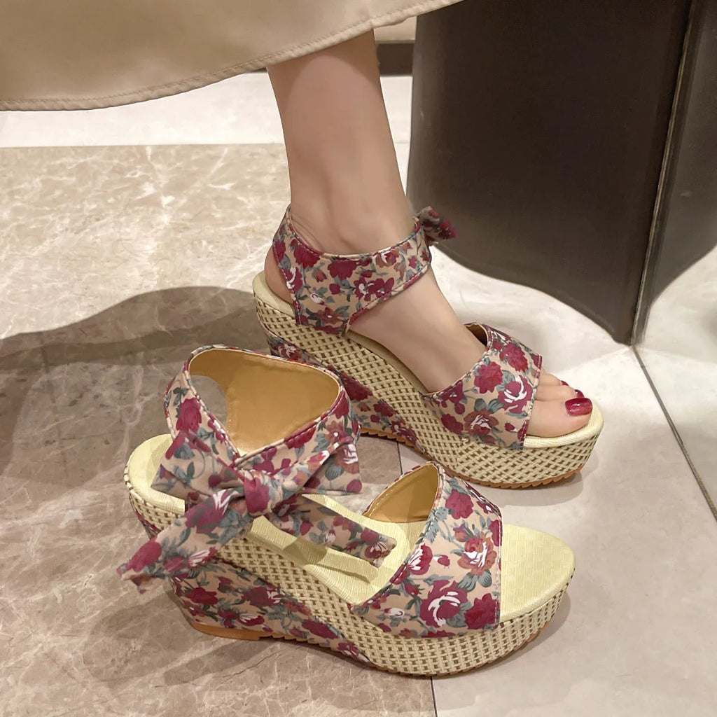 Women's wedge peep toe sandals with an ankle strap buckle in a floral pattern.