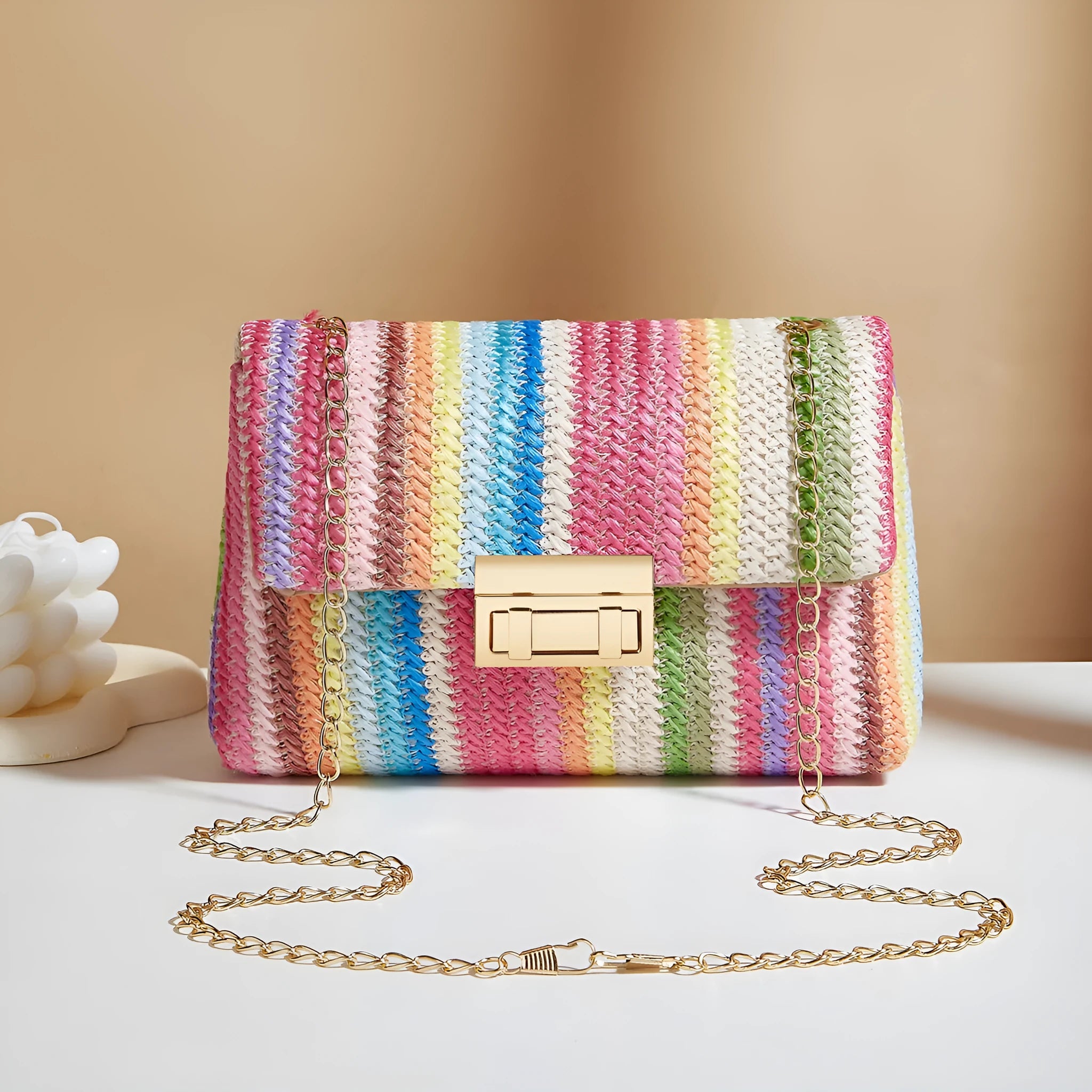 Soft woven straw women's cross-body bag in a small square shape, shown in rainbow colour with a single shoulder strap.