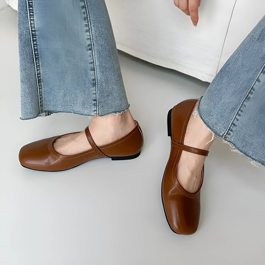 Women's black sheepskin Mary Jane flat shoes with round toe and flat rubber sole on a white background.