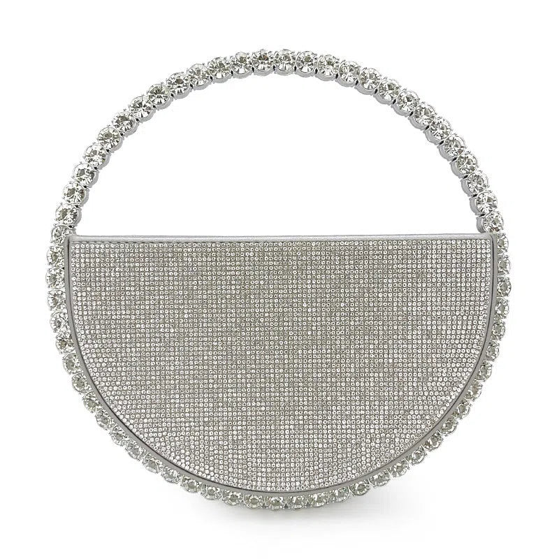 Round silver white PU evening bag with rhinestone details and crossbody strap on flat surface