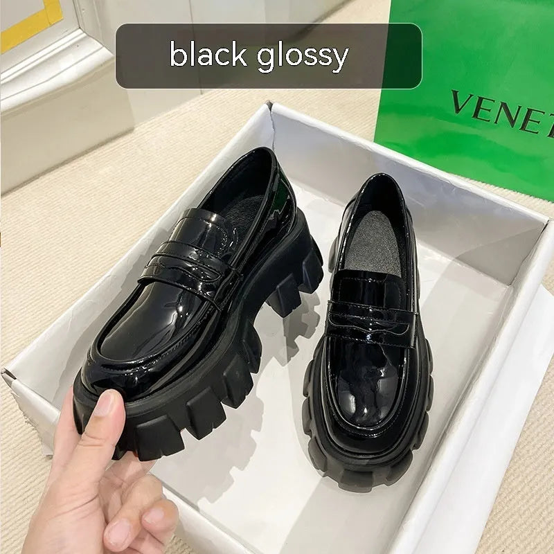 A pair of British style wide fit loafers in either matte or glossy patent leather with a shallow opening and rubber sole.