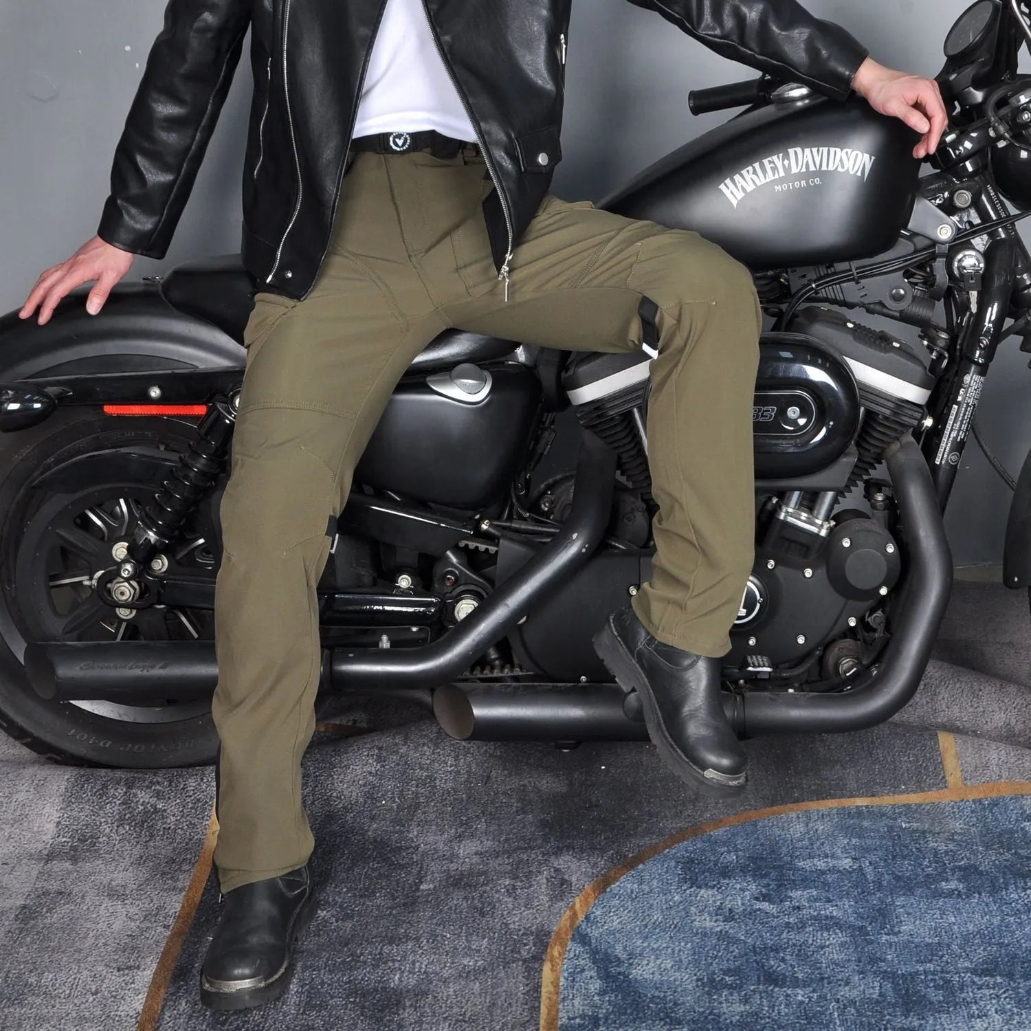 Men's green waterproof motorcycle trousers with belt and protective knee pads laid flat.