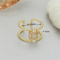 Gold-coloured asymmetric U-shaped open ring with an adjustable gap on a plain background.