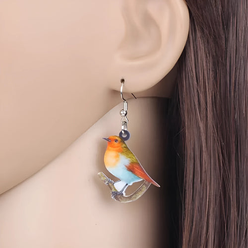 Pair of blue and white acrylic pendant earrings featuring a printed titmouse bird and snake design on geometric shapes.