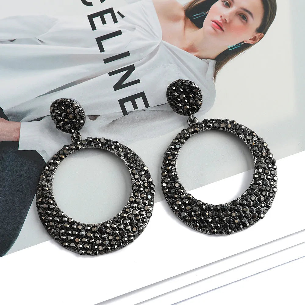 Colourful large pendant earrings with round diamond-shaped studs on a cartoon-style metal setting.