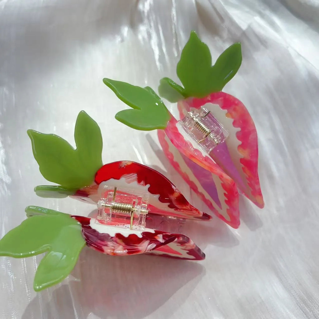 Close-up of a handmade strawberry hairpin in red on a pink background.