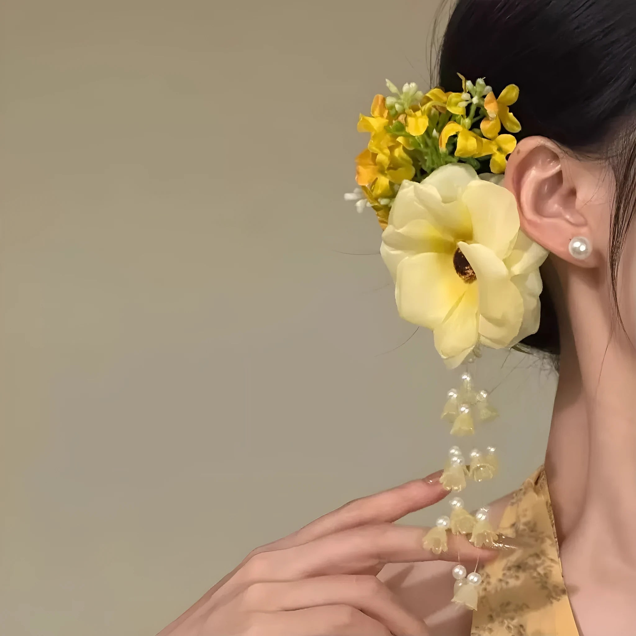 Handmade yellow floral hair clip with pearls and a long tassel on a side-clip grip.