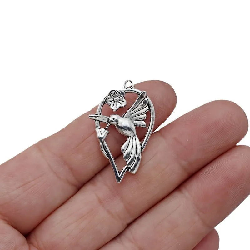 Close-up of a silver-tone alloy magpie charm pendant with engraved feather details on wings and tail for DIY jewellery.
