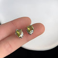 Pair of liquid olive green electroplated alloy stud earrings for women on a neutral background