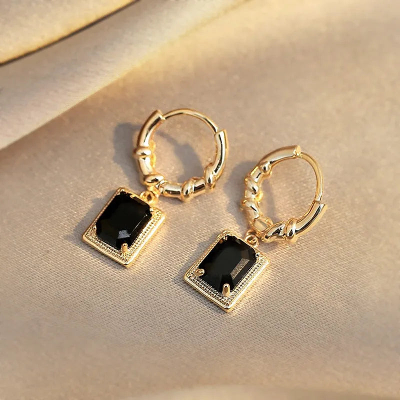 Close-up of women's geometric quadrilateral copper earrings with a black zircon stone and butterfly back.