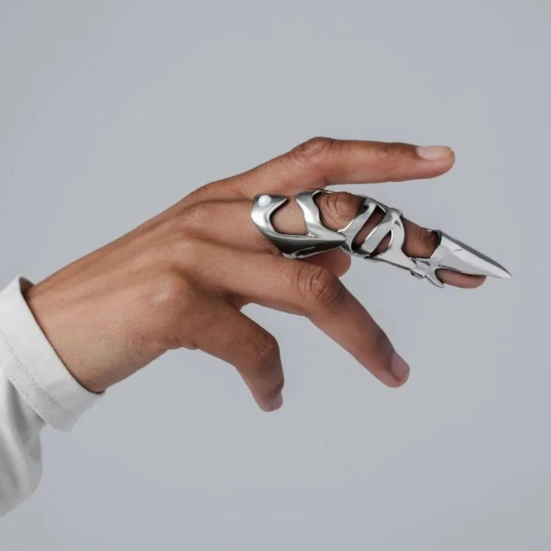 Silver punk armour finger stall ring on a finger, showing its one-piece, layered metal design.