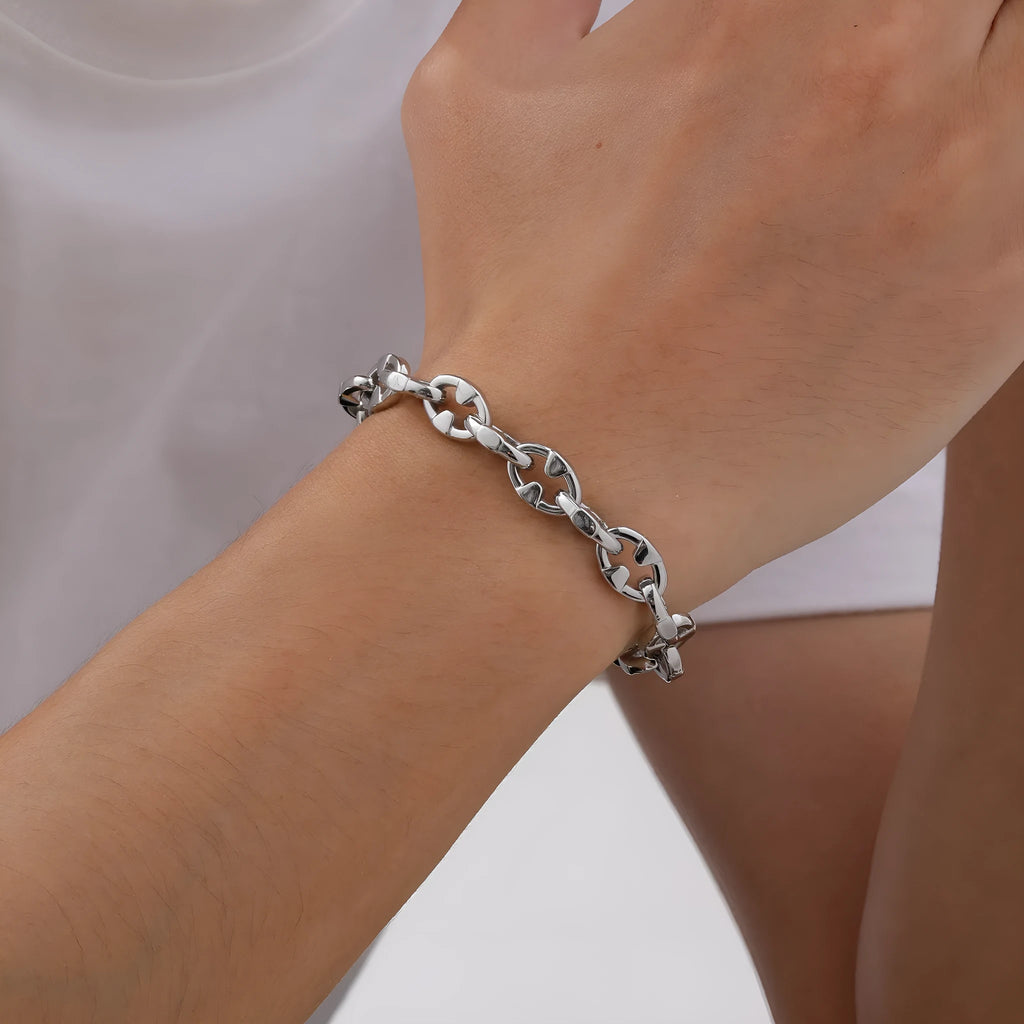 Close-up of a thick geometric chain bracelet made from polished stainless steel, on a wrist.
