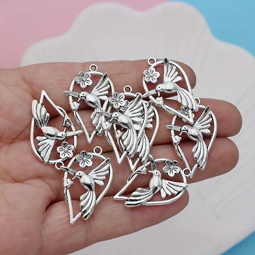 Close-up of a silver-tone alloy magpie charm pendant with engraved feather details on wings and tail for DIY jewellery.