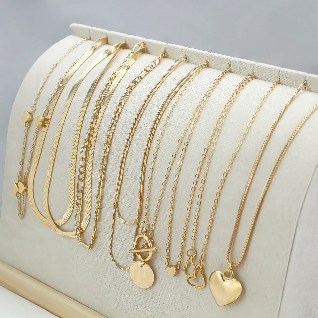Set of ten gold women's fashion necklaces with snake bone chains and adjustable length on a white background.