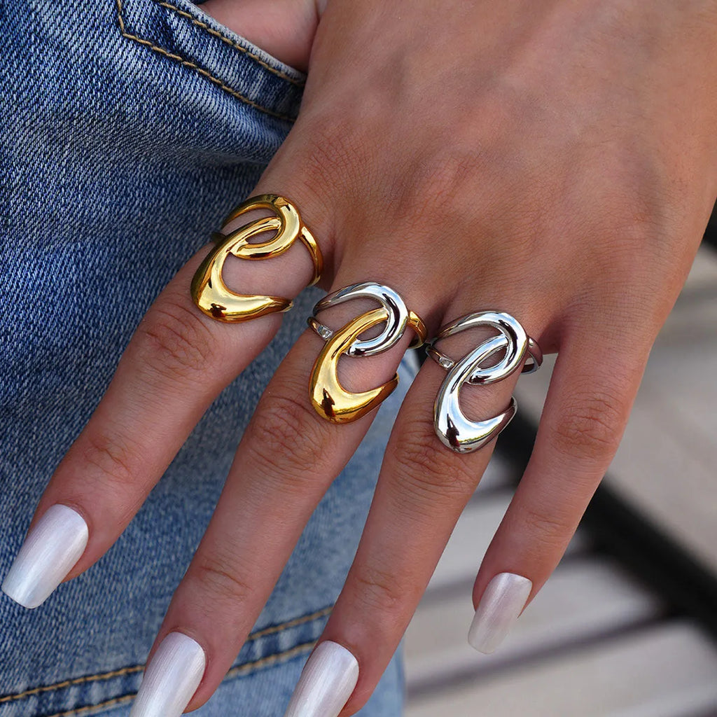 Geometric lines hollow out stainless steel ring with PVD gold plating on a neutral background