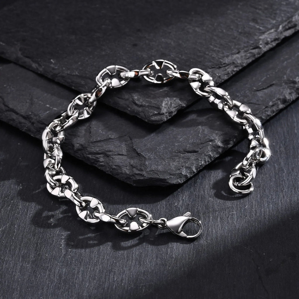 Close-up of a thick geometric chain bracelet made from polished stainless steel, on a wrist.
