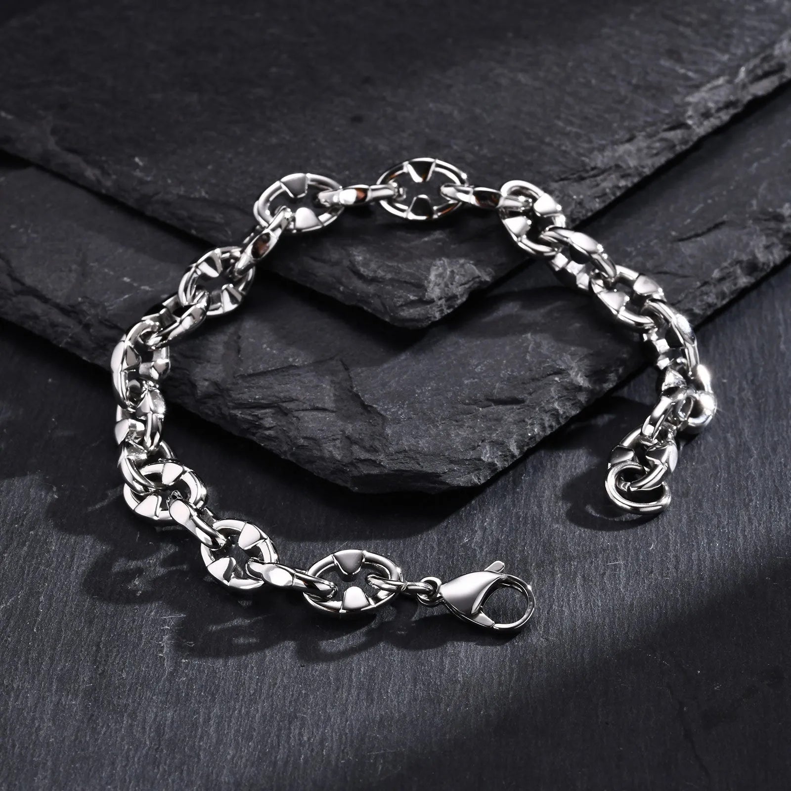 Close-up of a thick geometric chain bracelet made from polished stainless steel, on a wrist.