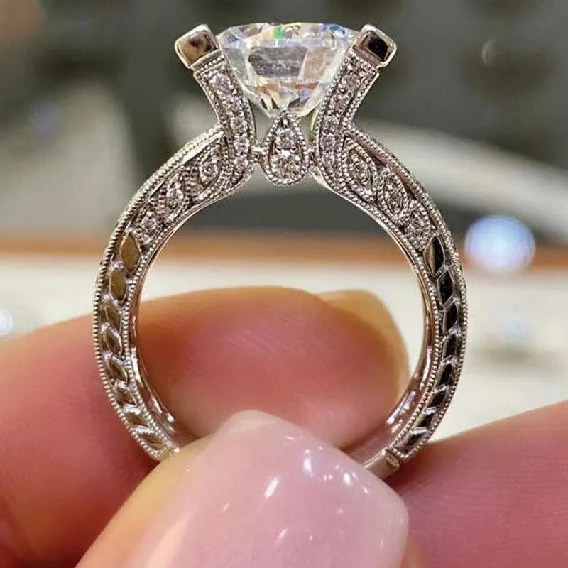 Geometric women's alloy ring with round detail in gold or white electroplated finish on a finger.
