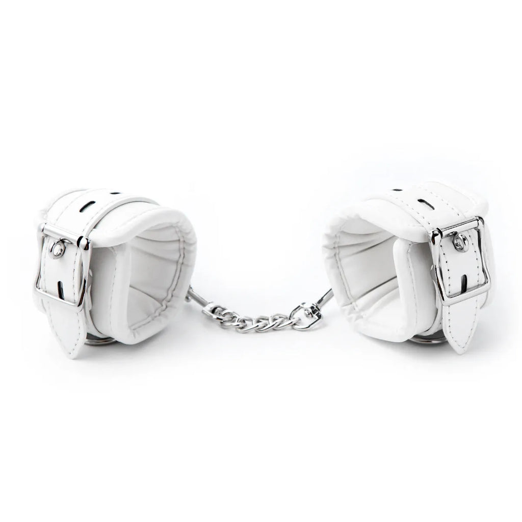 White PU sponge bondage set showing handcuffs, footcuffs, ankle bracelet, and neck scarf on a dark background.