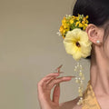 Handmade yellow floral hair clip with pearls and a long tassel on a side-clip grip.