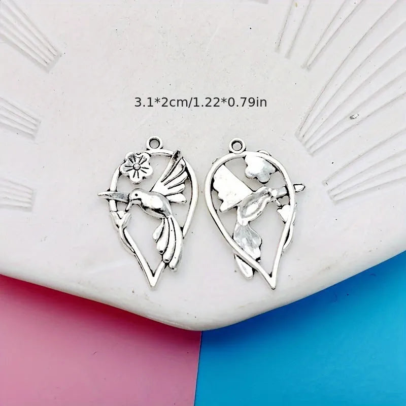Close-up of a silver-tone alloy magpie charm pendant with engraved feather details on wings and tail for DIY jewellery.