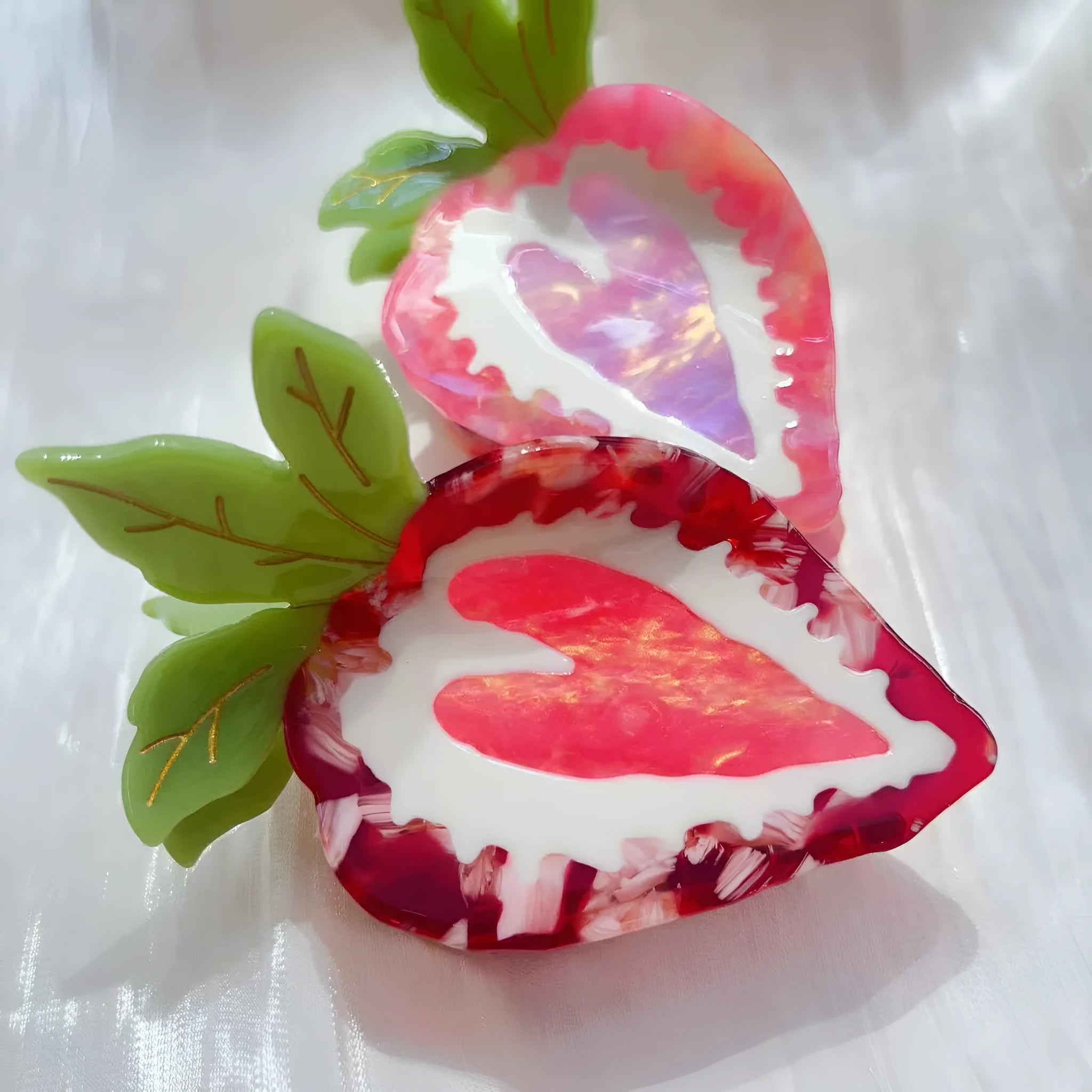 Close-up of a handmade strawberry hairpin in red on a pink background.