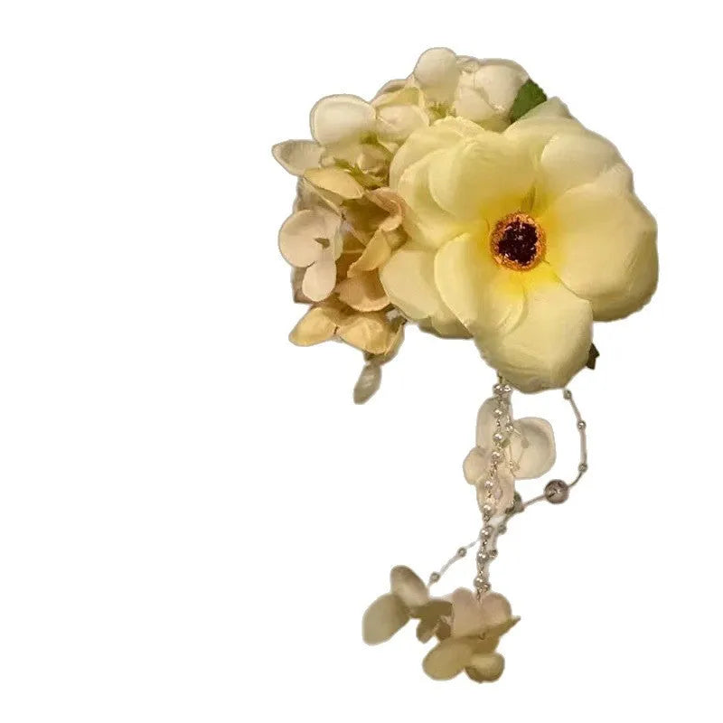 Handmade yellow floral hair clip with pearls and a long tassel on a side-clip grip.