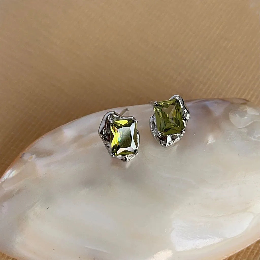 Pair of liquid olive green electroplated alloy stud earrings for women on a neutral background