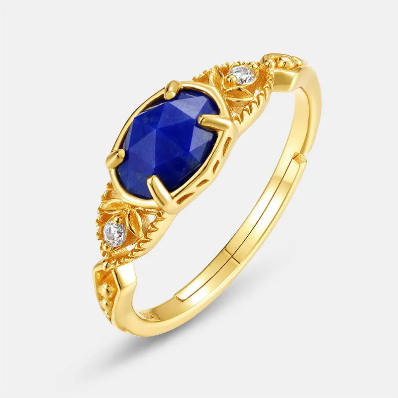 A silver geometric ring with a natural blue lapis lazuli stone, showing ellipse shape and round details.