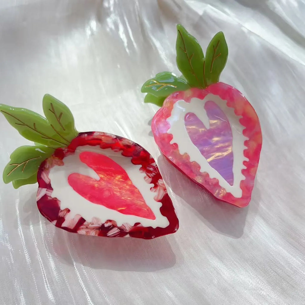 Close-up of a handmade strawberry hairpin in red on a pink background.