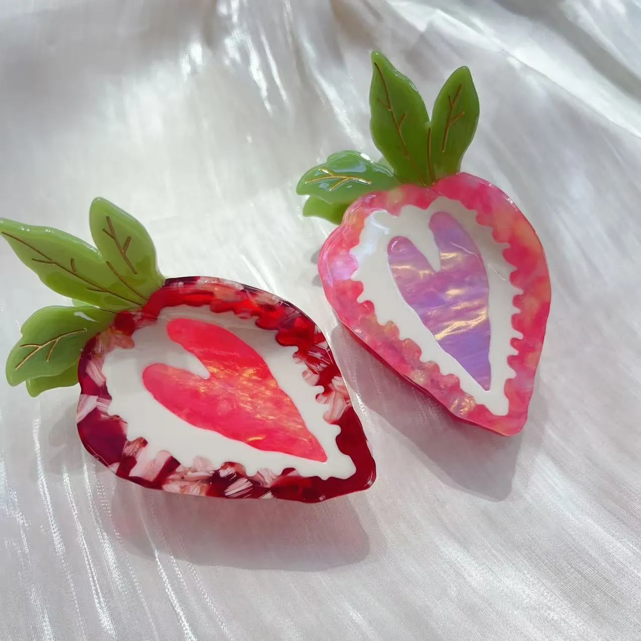 Close-up of a handmade strawberry hairpin in red on a pink background.