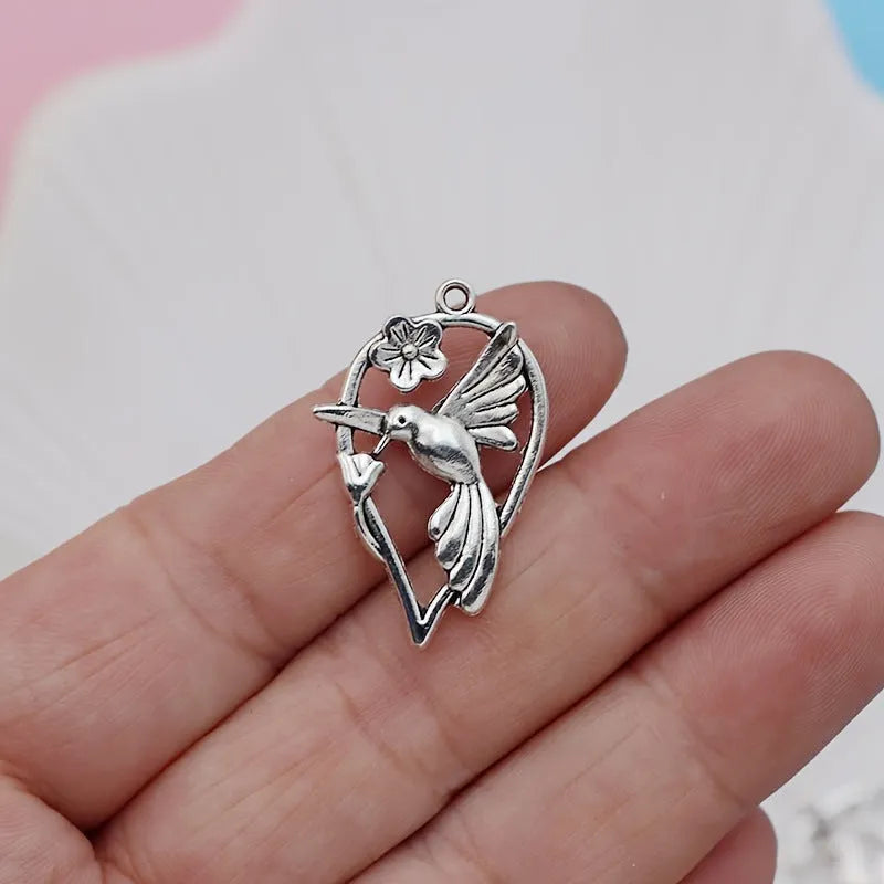 Close-up of a silver-tone alloy magpie charm pendant with engraved feather details on wings and tail for DIY jewellery.