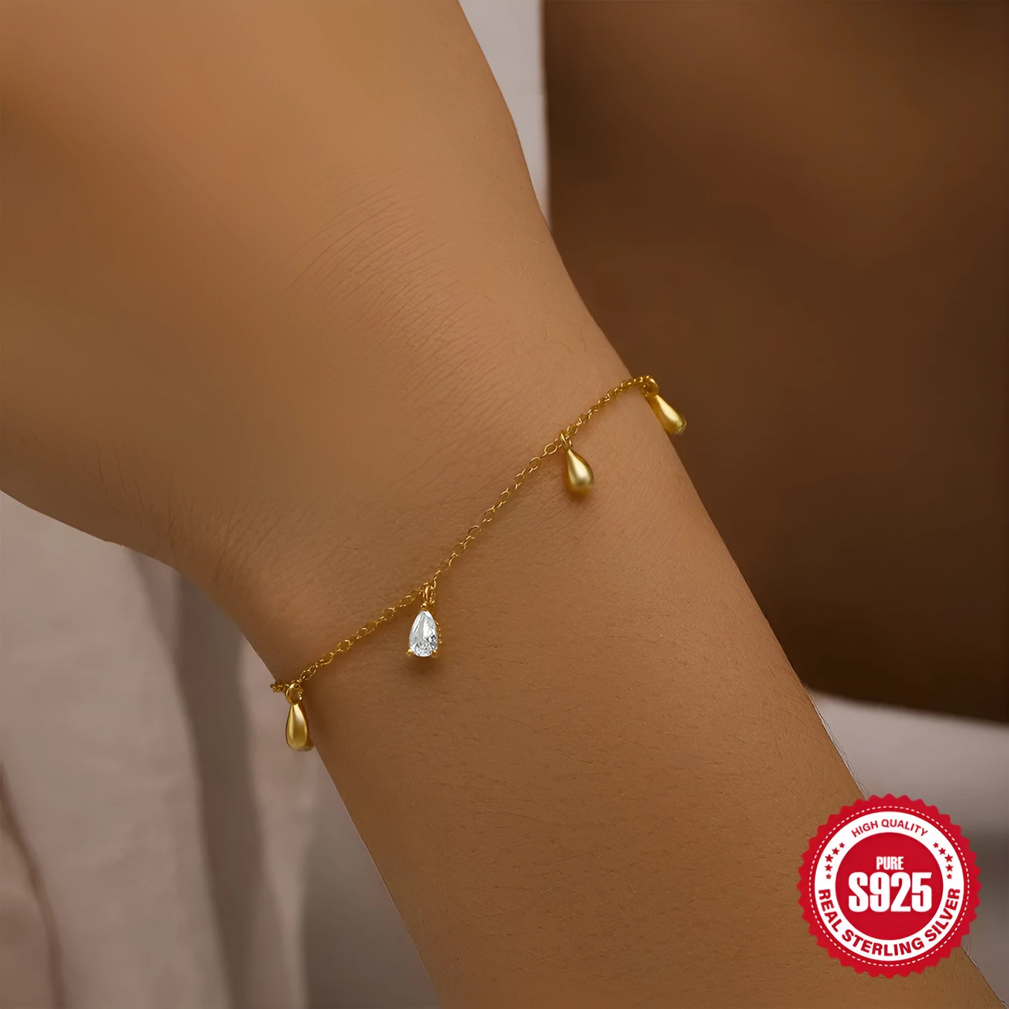 S925 sterling silver bracelet with gold tone water drop diamond pendant on a wrist.