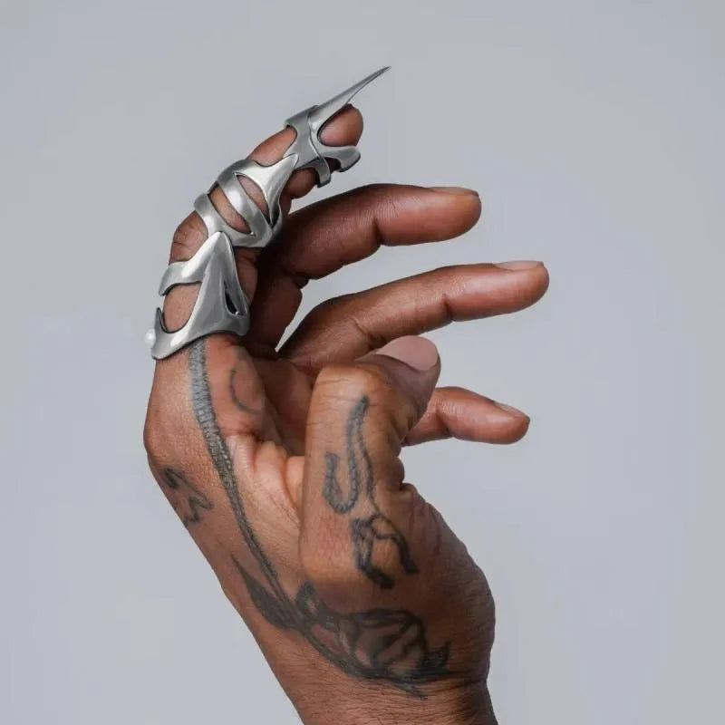 Silver punk armour finger stall ring on a finger, showing its one-piece, layered metal design.