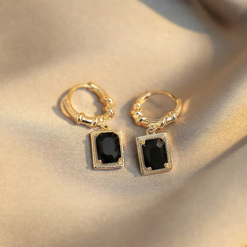 Close-up of women's geometric quadrilateral copper earrings with a black zircon stone and butterfly back.