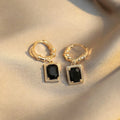 Close-up of women's geometric quadrilateral copper earrings with a black zircon stone and butterfly back.