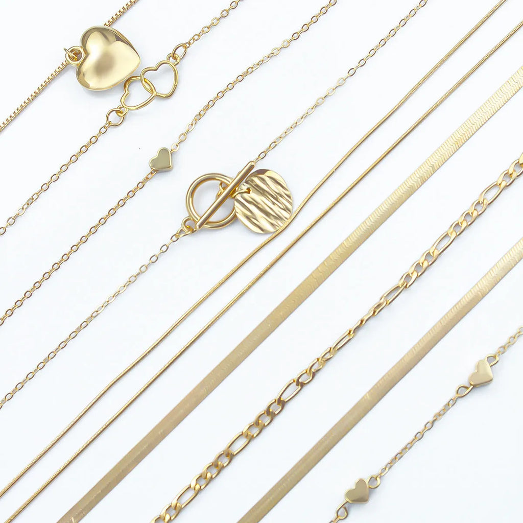 Set of ten gold women's fashion necklaces with snake bone chains and adjustable length on a white background.